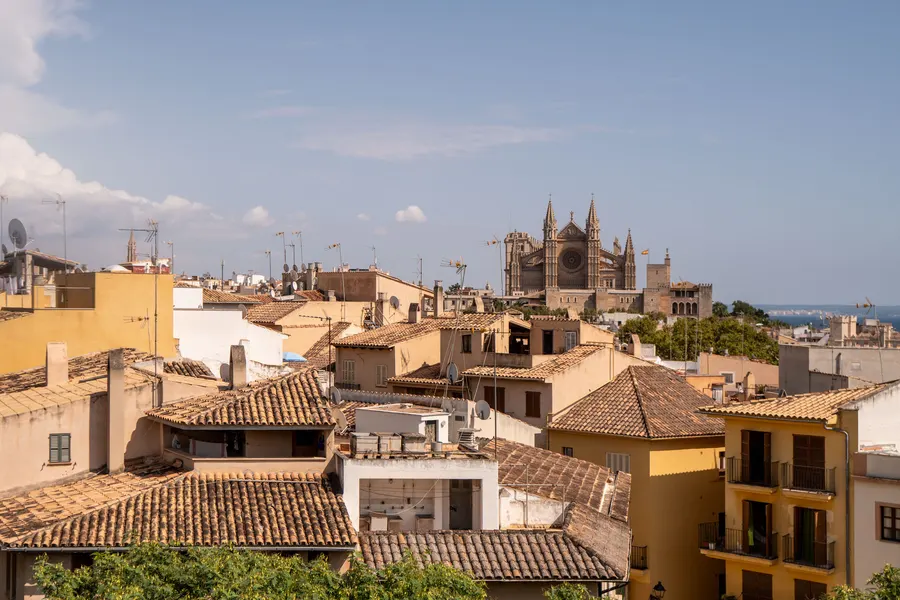 Blick von der Bastion über die Ziegeldächer der Altstadt von Palma zur Kathedrale La Seu und zum Meer dahinter.

