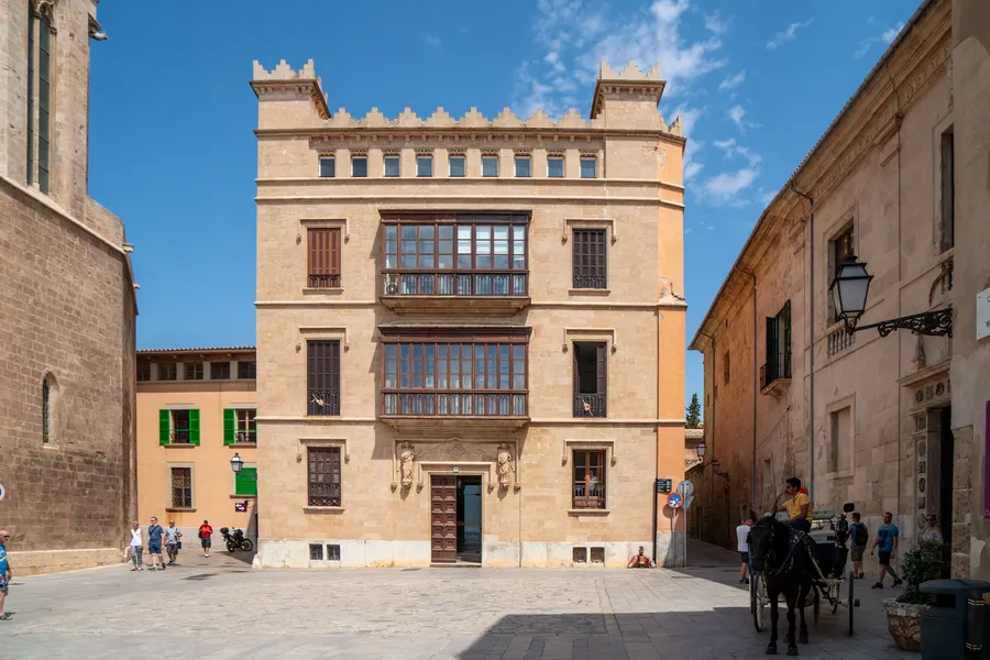 Der Bischofspalast neben der Kathedrale von Palma, ein hoher Steinbau mit Zinnen und schmalen Fenstern.
