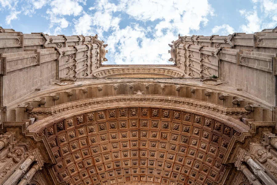 Der tief gestufte Kassettenbogen über einem Portal der Kathedrale von Palma, aus hellem Sandstein.
