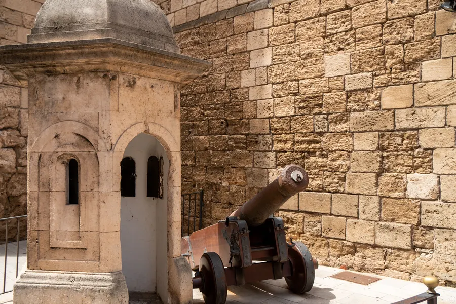 Steinerne Wachtrupp-Garita mit Kuppeldach und eine alte Kanone an der Mauer des Palau de l'Almudaina in Palma.
