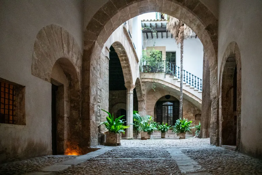 Innenhof des Can Catlar del Llorer an der Carrer de Can Savella in Palma, mit Spitzbogen, Galerie und Pflanzen in Töpfen.
