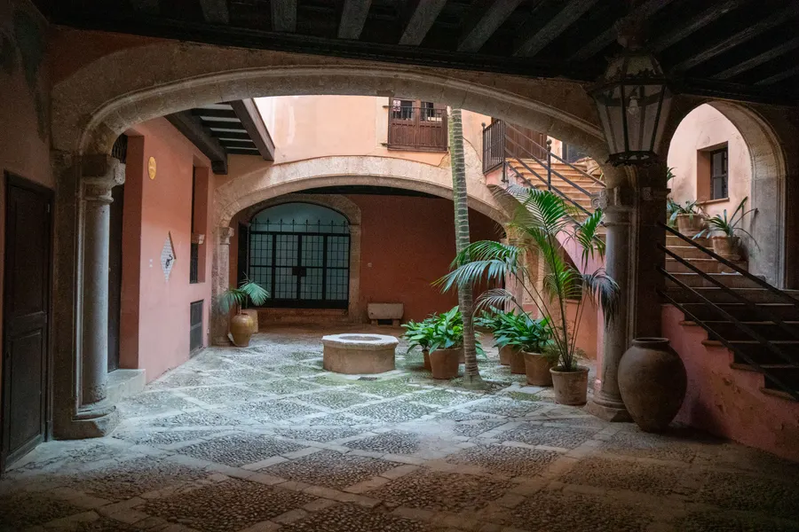 Innenhof des Stadtpalastes Can Juny in Palma mit Bögen, offener Treppe und großen Tonkrügen.
