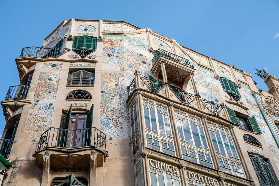 Die Jugendstilfassade des Can Forteza Rey in Palma mit Keramikmosaik, geschwungenen Fenstern und schmiedeeisernen Balkonen.
