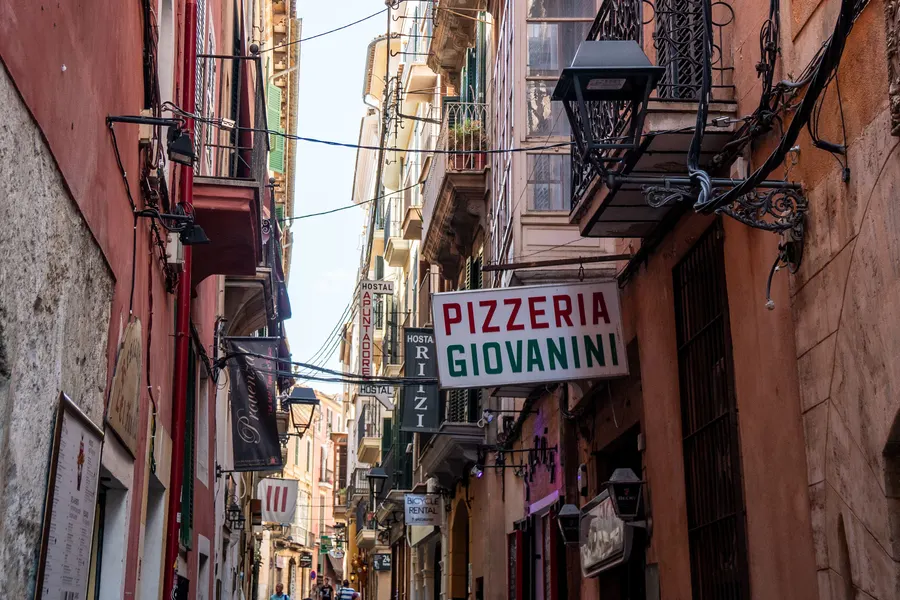 Die Carrer dels Apuntadors in Palma, eine enge Gasse mit Lokalschildern, Laternen und bunten Fassaden.