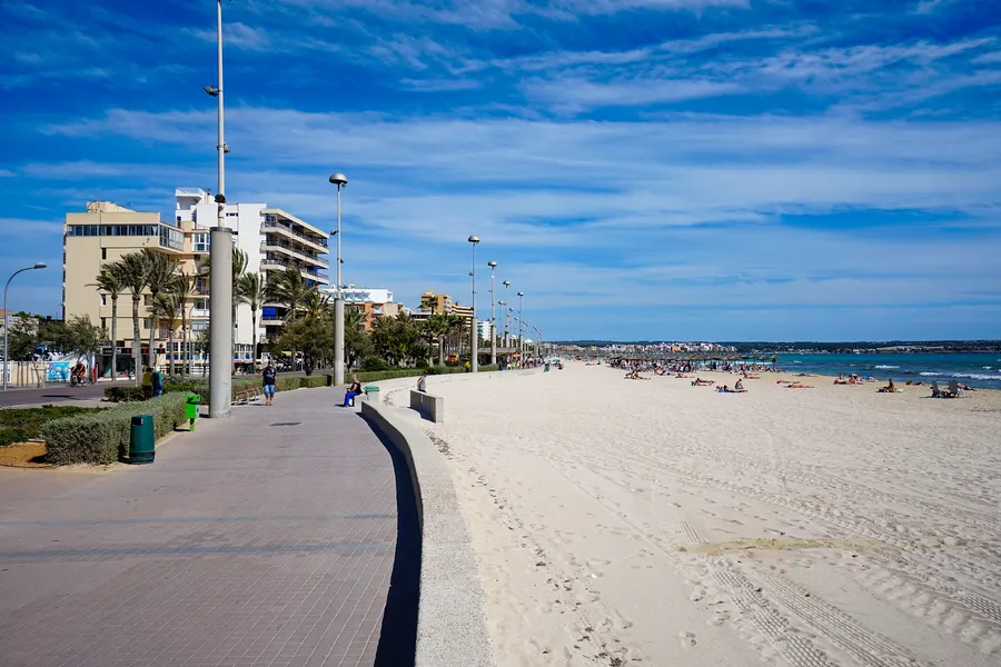 Der geschwungene weiße Bau des Palma Aquarium an der Platja de Palma unter blauem Himmel.
