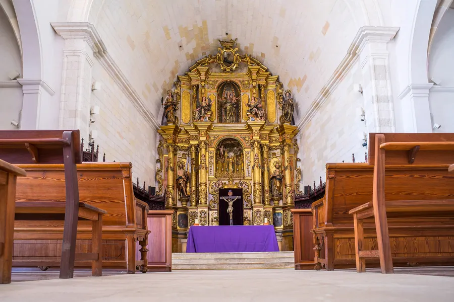 Innenraum der Kirche von Santa Margalida mit vergoldetem Barockaltar, dunklen Holzbänken und hellen Wänden.
