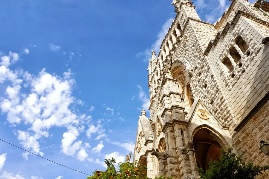 Der reich gegliederte Turm der Kirche Sant Bartomeu in Sóller, steil von unten gegen den Himmel fotografiert.