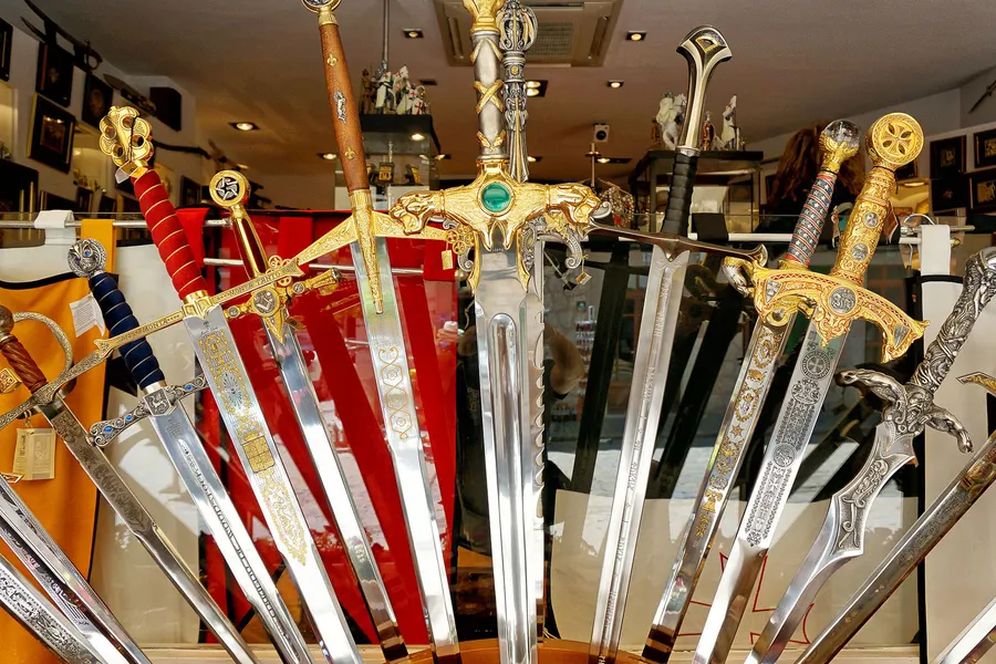 Dekorative Schwerter und Säbel mit verzierten Griffen in einem Souvenirschaufenster in Valldemossa.
